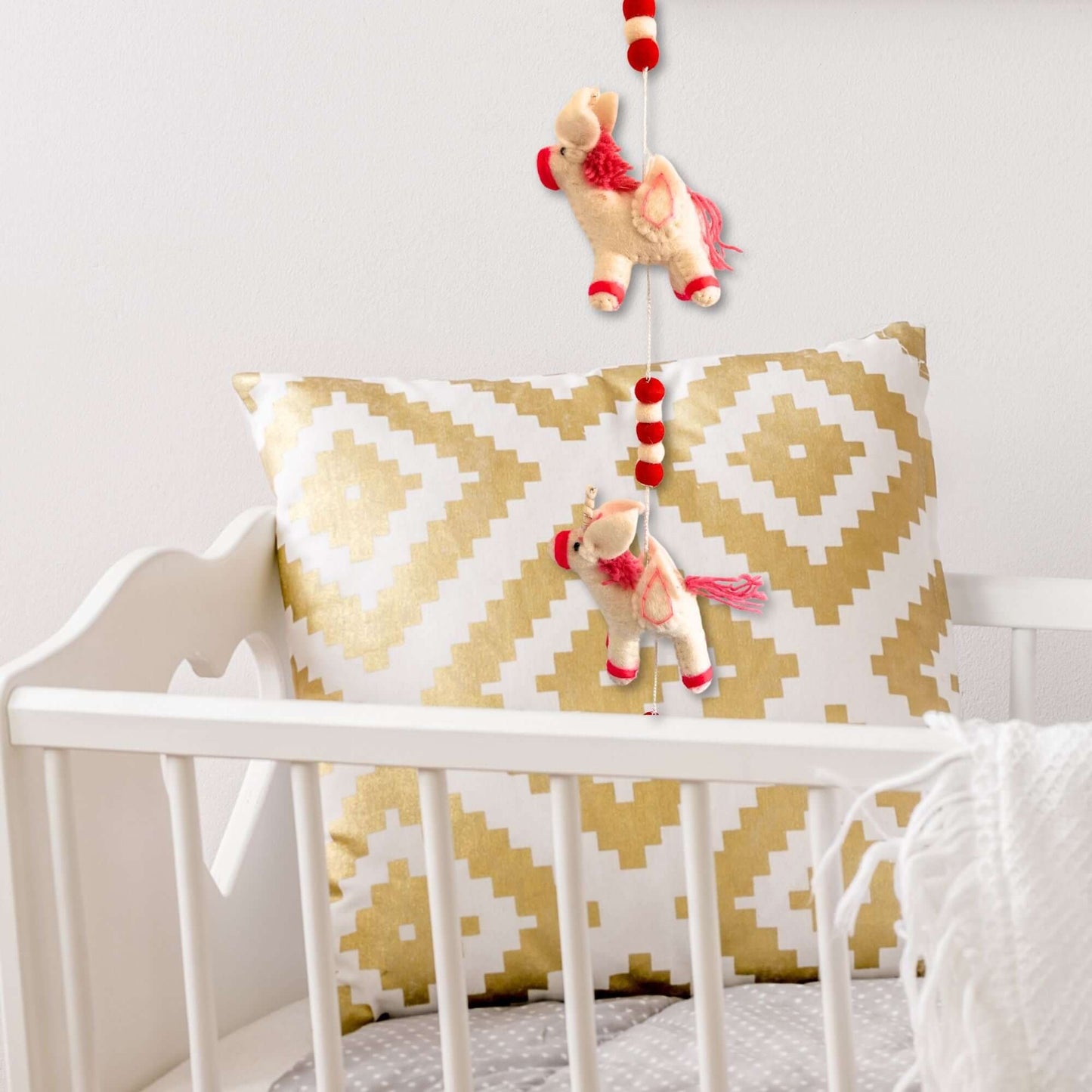 Felt Wall Hanging Unicorns adorning a nursery pillow, adding a whimsical touch to children's decor.