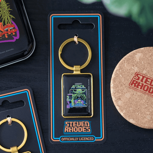 Keychain in packaging with 'Steven Rhodes' branding on a dark surface