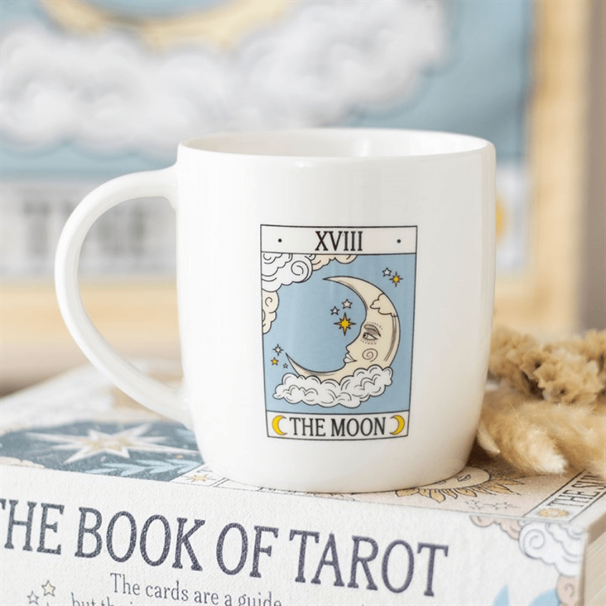 White mug with 'The Moon' tarot card design on a book titled 'The Book of Tarot'.