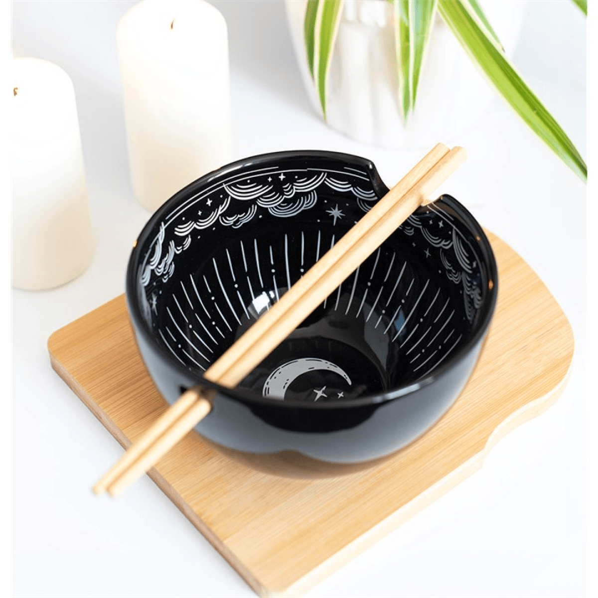 Spellbound Sky Noodle Bowl and Chopsticks Set with black ceramic bowl and wooden chopsticks on bamboo board.