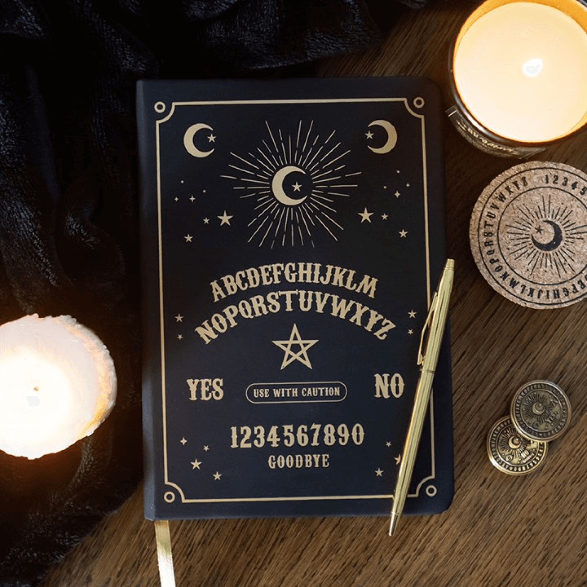 Ouija board with candles and coins on a wooden surface