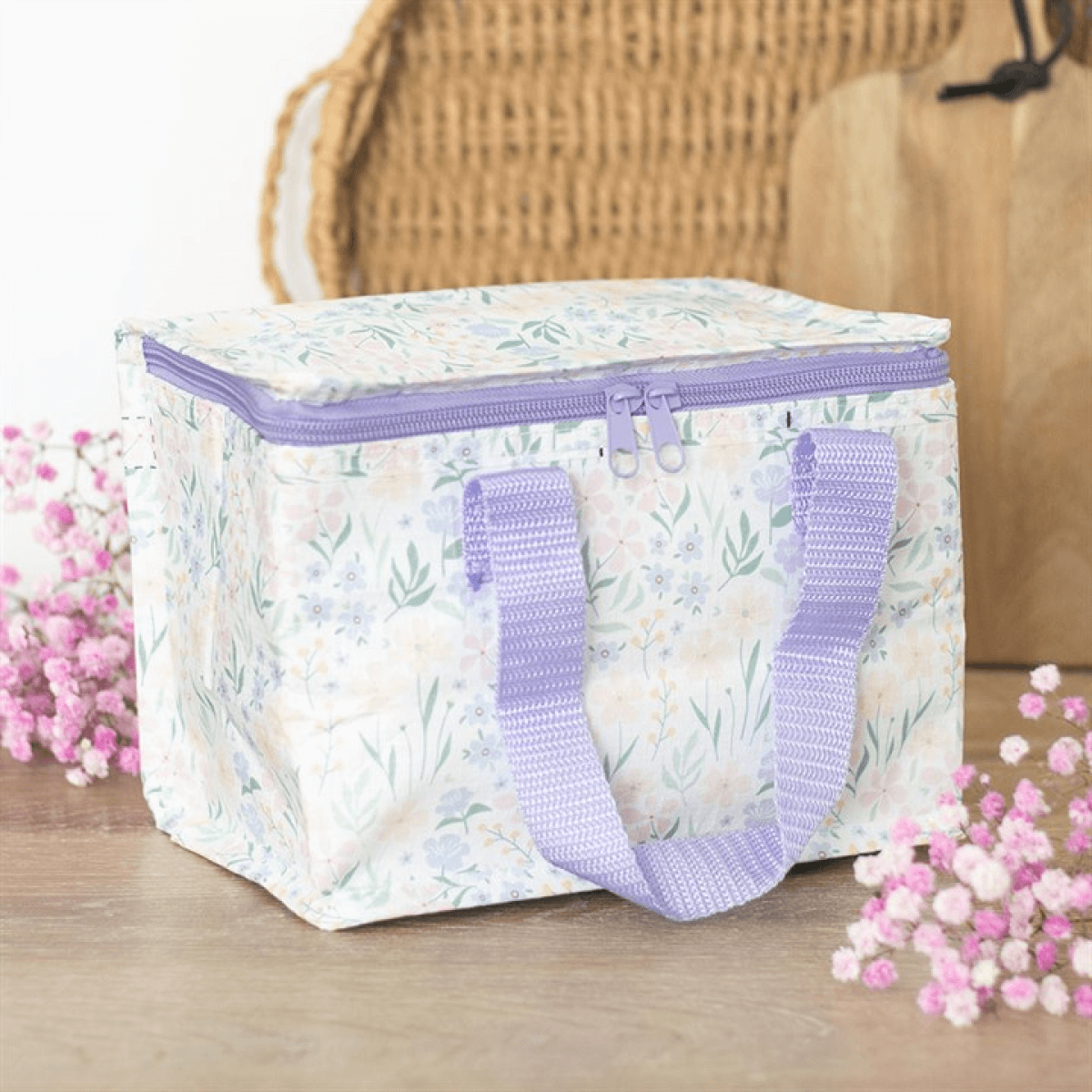 Floral-patterned storage box with a purple zipper and handles on a wooden surface with flowers.
