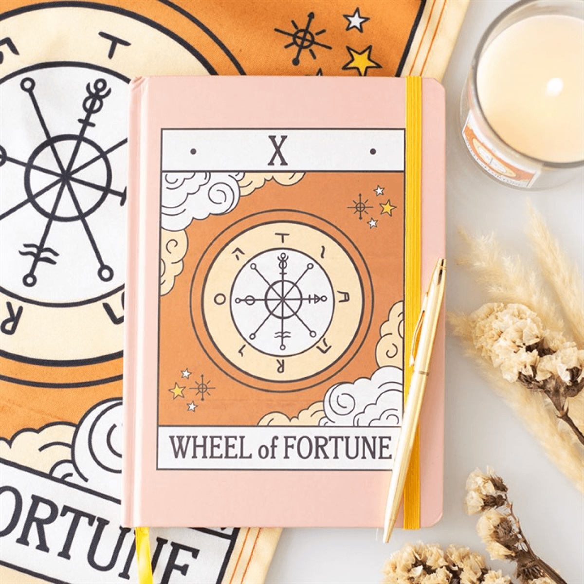 Notebook with 'Wheel of Fortune' design on a surface with tarot card symbols.
