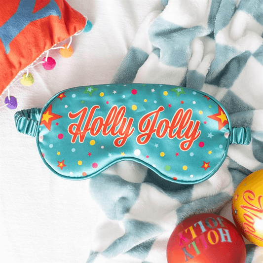 Sleep mask with 'Holly Jolly' text on a soft fabric background