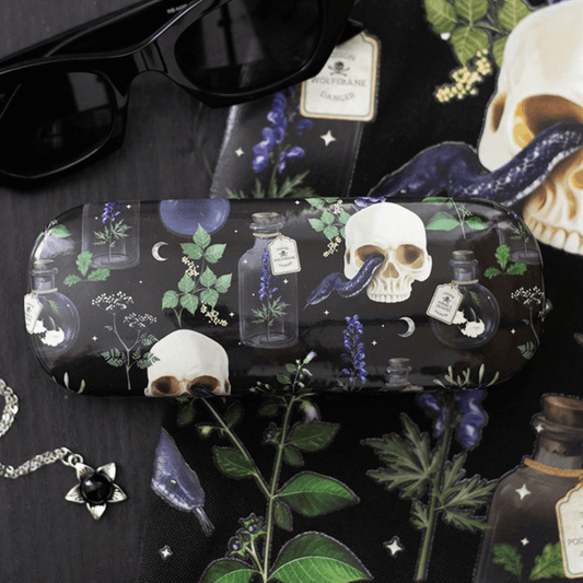 Sunglasses on a black surface with a decorative case featuring skulls, bottles, and plants.