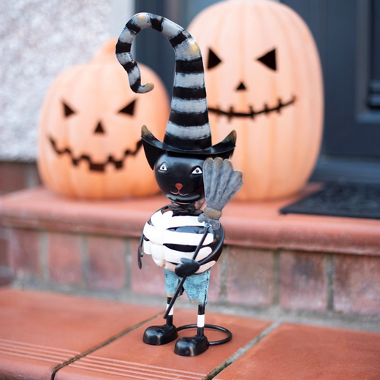 Cheerful metal black cat ornament with a witch hat, standing beside Halloween pumpkins.