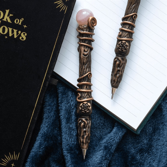 Decorative pen with a pink gemstone on an open book