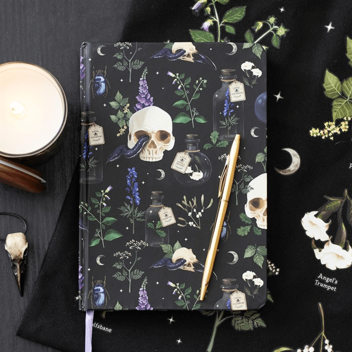 Dark notebook with skull and floral design on a decorative background with crystals and candles