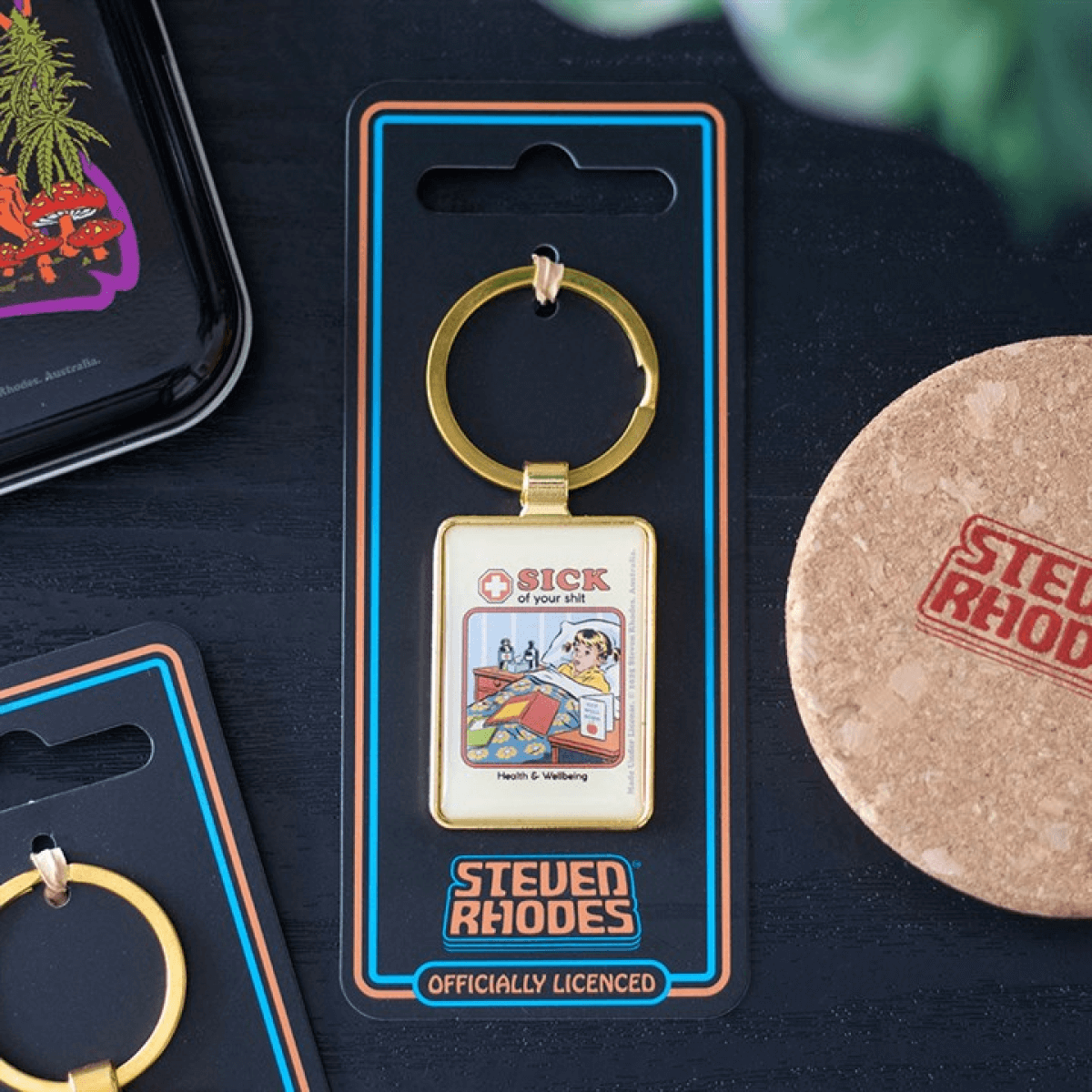 Keychain in packaging with 'Steven Rhodes' branding on a dark surface.