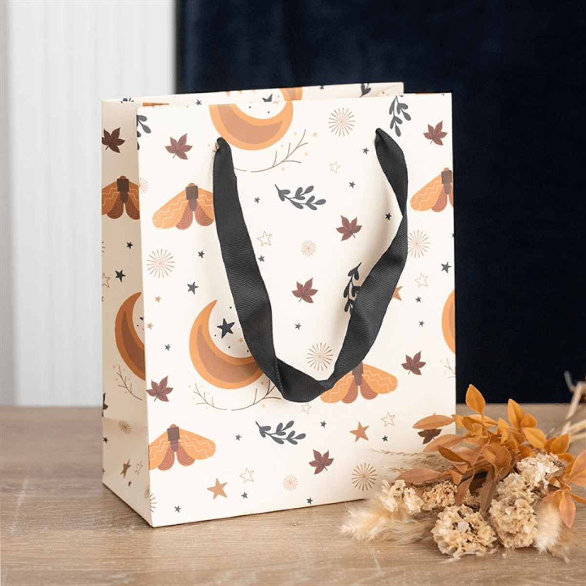 Gift bag with autumn-themed design on a wooden surface